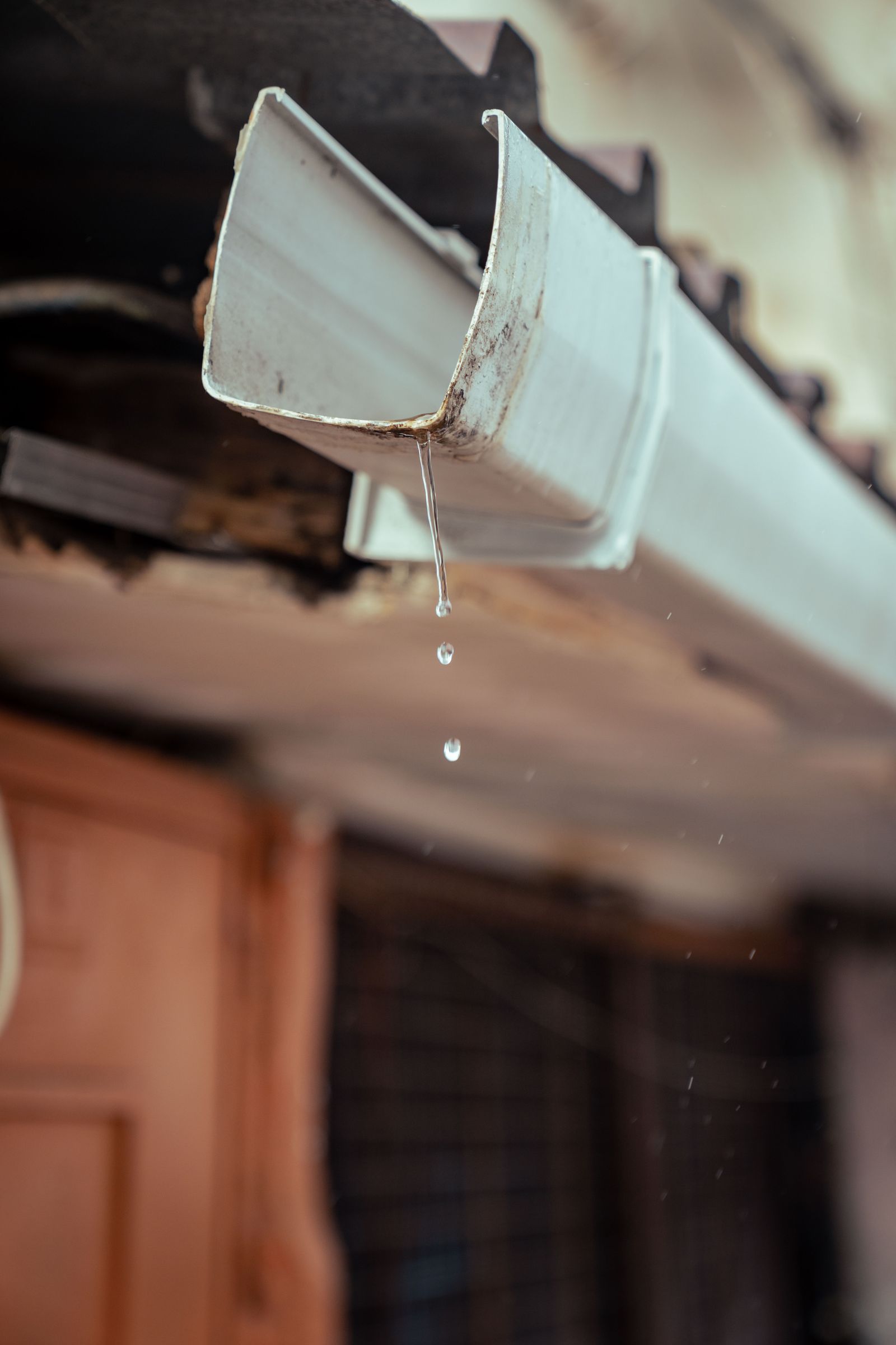 Rainwater dripping from the edge of a roof gutter