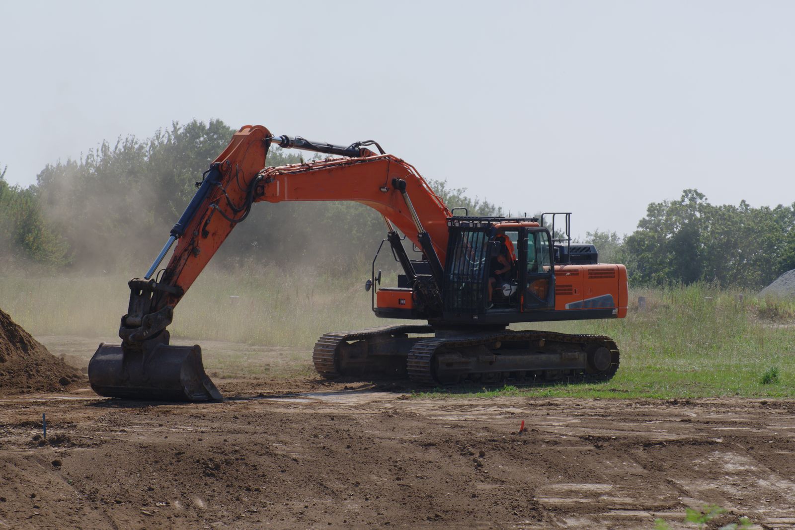 Excavator leveling bare soil for grading